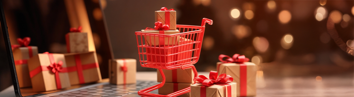 shopping cart with christmas gifts in front of laptop